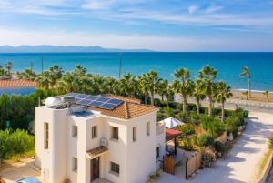 uma casa com painéis solares em cima dela junto à praia em Villa Jan Lui em Argaka