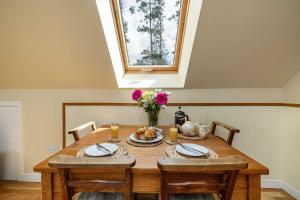 comedor con mesa de madera y ventana en The Barn at Dormouse Cottage en Selkirk