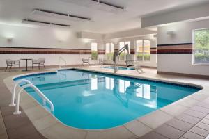 a large pool in a hotel room with a table and chairs at Hilton Garden Inn Fort Wayne in Fort Wayne
