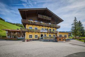 a large yellow building with a balcony with flowers on it at Eibinghof BED & BREAKFAST & SWIM in Saalbach Hinterglemm