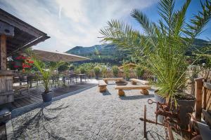 a patio with benches and tables and palm trees at Eibinghof BED & BREAKFAST in Saalbach-Hinterglemm