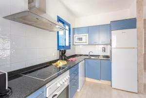 a kitchen with blue cabinets and a white refrigerator at Villa Tropical in Playa Blanca