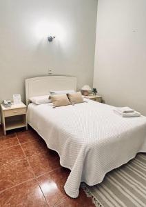 1 dormitorio con 1 cama blanca grande y 2 mesas en Hotel Renacer Tarija en Tarija