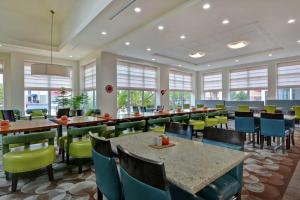 uma sala de jantar com mesas, cadeiras e janelas em Hilton Garden Inn and Fayetteville Convention Center em Fayetteville