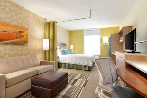 吉列的住宿－吉列希爾頓欣庭套房酒店，酒店客房配有一张床、一张沙发和一张书桌。