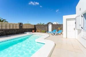 una piscina con sillas azules y una casa en Villa Zoe, en Los Pocillos
