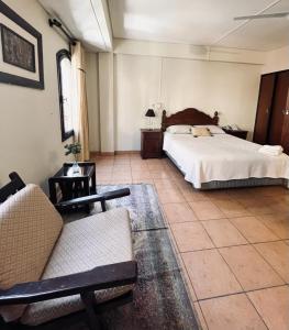 a bedroom with a bed and a couch and chairs at Hotel Renacer Tarija in Tarija