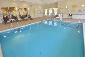 a large swimming pool in a large room with tables and chairs at Hilton Garden Inn Greensboro in Greensboro