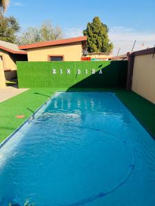 a blue swimming pool in front of a house at Zindiza Guesthouse in Witbank