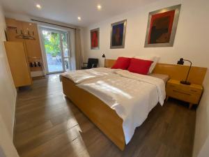 een slaapkamer met een groot bed met 2 rode kussens bij DOMAINE DES CAPUCINS 