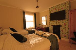 um quarto de hotel com duas camas e uma televisão de ecrã plano em The Crow's Nest em Broadstairs