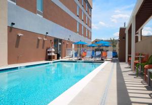 a swimming pool with chairs and umbrellas next to a building at Home2 Suites by Hilton Greenville Airport in Greenville