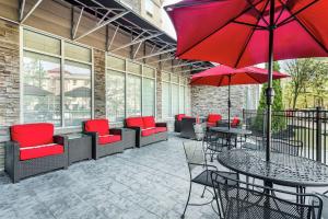 un patio con mesas, sillas y sombrillas rojas en Hilton Garden Inn Gainesville, en Gainesville