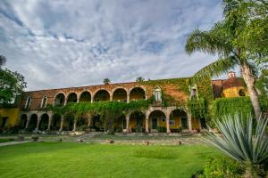 un edificio cubierto de hiedra con un patio verde en Hacienda El Carmen Hotel & Spa, en Portes Gil