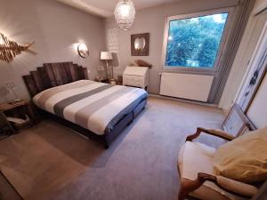 1 dormitorio con cama, ventana y silla en Woodland's House, en Hermanville-sur-Mer