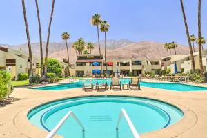 a swimming pool at a resort with palm trees at Retro-Inspired Palm Springs Condo with Pool View! in Palm Springs