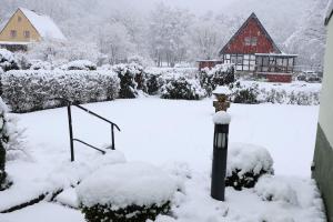 a yard covered in snow with a red house at Ferienhaus Alte Maßschneiderei in Schleiden