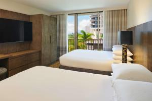 ホノルルにあるEmbassy Suites by Hilton Waikiki Beach Walkのベッド2台とテレビが備わるホテルルームです。