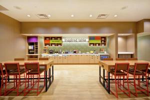 休斯顿Home2 Suites At The Galleria的一个带木桌和红色椅子的大厨房