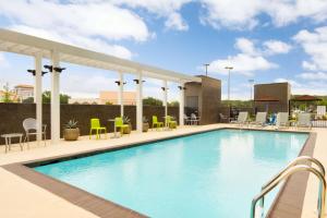einen Pool in einem Hotel mit Stühlen und Tischen in der Unterkunft Home2 Suites by Hilton Houston Stafford - Sugar Land in Stafford