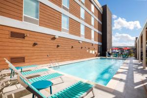 ヒューストンにあるHome2 Suites by Hilton Houston Bush Intercontinental Airport Iah Beltway 8の建物の隣にスイミングプール(長椅子付)があります。