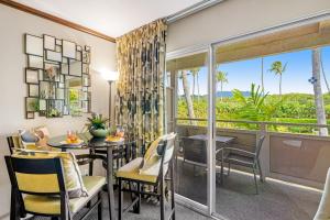 a dining room with a table and chairs and a large window at Plantation Hale J11 in Kapaa