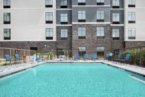 a swimming pool with blue chairs and a building at Homewood Suites By Hilton Houston Memorial in Houston