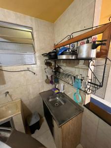eine kleine Küche mit einem Waschbecken in einem Zimmer in der Unterkunft Kitnets Itapuã Residência - 1 Minuto de Caminhada Ate a Praia in Salvador