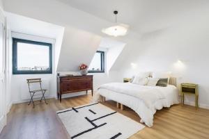 a white bedroom with a bed and a wooden floor at Superbe appartement de 120m2 et 2 balcons, à 10min à pieds de la plage - 3 chambres - parking privé in Le Pouliguen