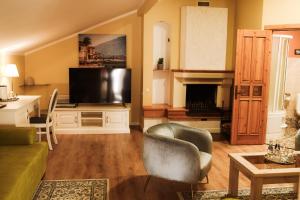 ein Wohnzimmer mit einem TV, einem Sofa und einem Stuhl in der Unterkunft Jolanta in Alūksne
