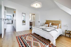 a white bedroom with a large bed and a rug at Superbe appartement de 120m2 et 2 balcons, à 10min à pieds de la plage - 3 chambres - parking privé in Le Pouliguen