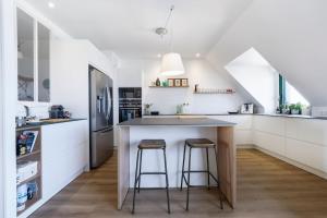 una cocina con una isla con 2 taburetes en Superbe appartement de 120m2 et 2 balcons, à 10min à pieds de la plage - 3 chambres - parking privé en Le Pouliguen