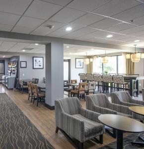 Una sala de espera con sillas y mesas y un bar. en Hampton Inn Houston I-10 West-Energy Corridor, en Houston