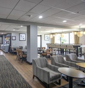 a waiting room with chairs and tables and a bar at Hampton Inn Houston I-10 West-Energy Corridor in Houston