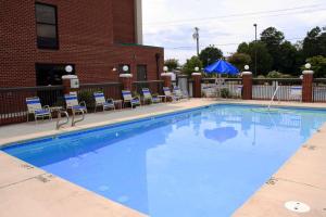 a large blue swimming pool with chairs and a building at Hampton Inn High Point in Archdale