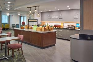 a large kitchen with a counter and tables and chairs at Hampton Inn by Hilton Harrisburg West in Mechanicsburg