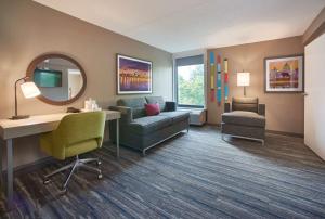 a living room with a couch and a desk and a mirror at Hampton Inn by Hilton Harrisburg West in Mechanicsburg