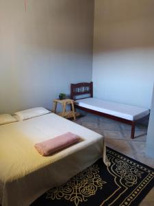 Un dormitorio con 2 camas y un banco en una habitación en Hostel do Cerrado en Cavalcante