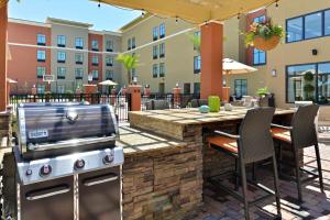 une terrasse avec un barbecue et une table avec des chaises dans l'établissement Homewood Suites by Hilton Houma, à Houma