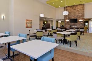 a dining room with tables and chairs and a tv at Homewood Suites by Hilton Houma in Houma