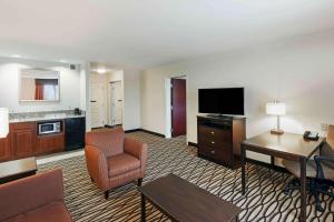 um quarto de hotel com uma área de estar com televisão e uma secretária em Hampton Inn & Suites Morgan City em Morgan City