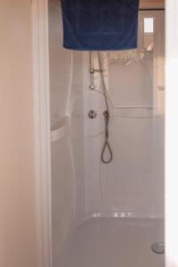 a white shower with a blue towel hanging from a door at Landgoed Omorika in Ravels