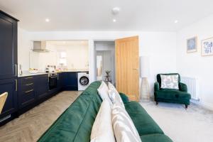 a living room with a green couch and a kitchen at CRINGLE COTTAGE, The Lanes Cottages, Stokesley in Stokesley