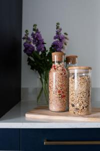 trois bocaux de graines sur un comptoir avec un vase de fleurs violettes dans l'établissement CRINGLE COTTAGE, The Lanes Cottages, Stokesley, à Stokesley
