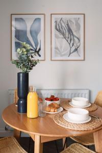 CRINGLE COTTAGE, The Lanes Cottages, Stokesley في ستوكيسلي: طاولة خشبية مع لوحات من الطعام و مزهرية من الزهور
