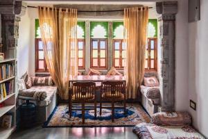 ウダイプールにあるLassi Guest Houseのテーブルと椅子2脚、窓が備わる客室です。