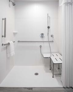 a white bathroom with a shower and a bench at Hilton Garden Inn Iowa City Downtown University in Iowa City