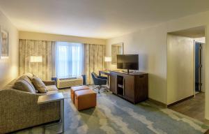 een hotelkamer met een bank, een bureau en een televisie bij Hampton Inn & Suites Jackson Coliseum in Jackson