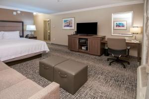 Habitación de hotel con cama, escritorio y TV. en Hampton Inn & Suites Ridgeland en Ridgeland
