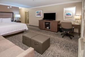 里奇兰Hampton Inn & Suites Ridgeland的配有床、书桌和电视的酒店房间